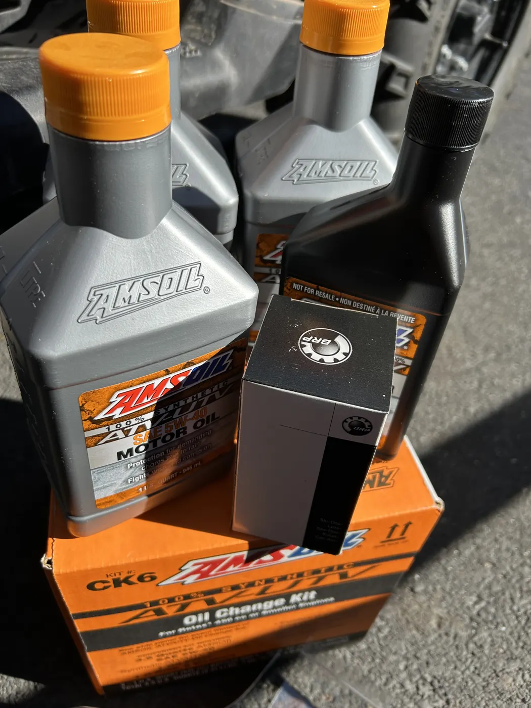 Close-up of AMSOIL Synthetic ATV/UTV Motor Oil quarts and an oil filter on top of an AMSOIL ATV/UTV Oil Change Kit box