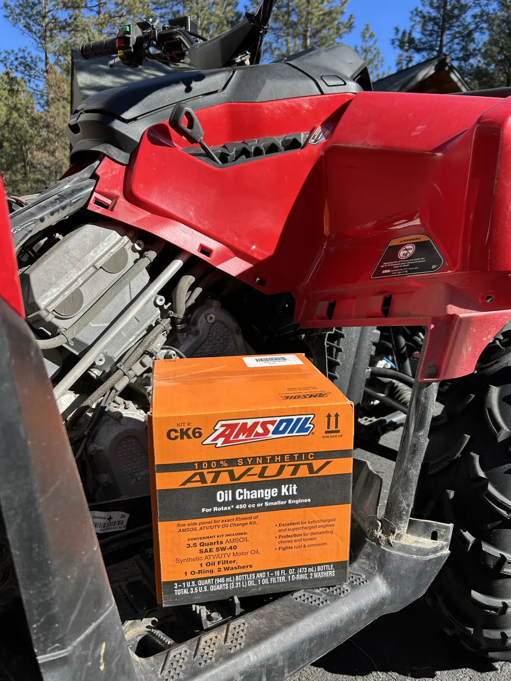 AMSOIL ATV/UTV oil change kit next to a red side-by-side